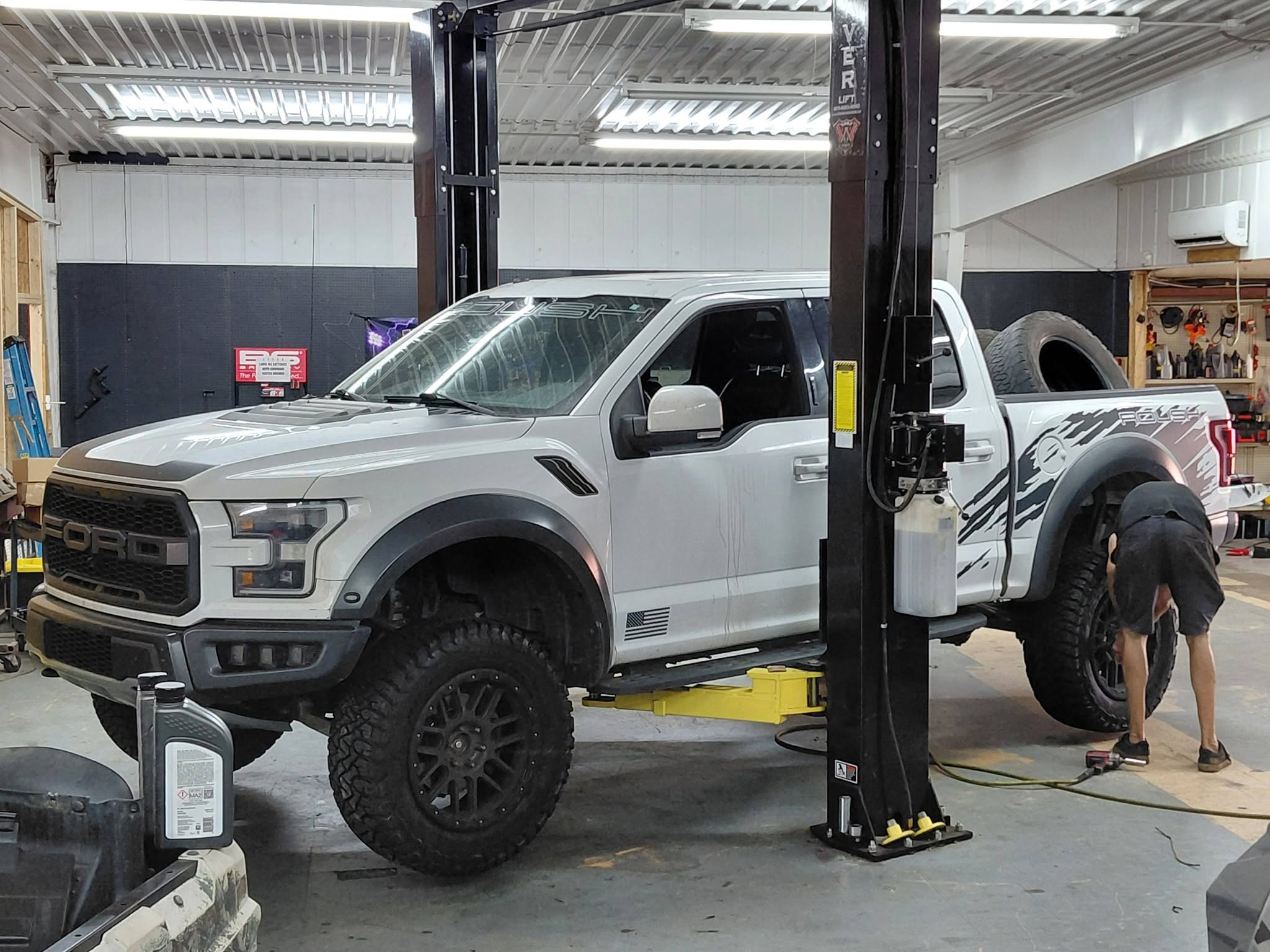 White Ford pickup being serviced on a lift in the Casslake shop